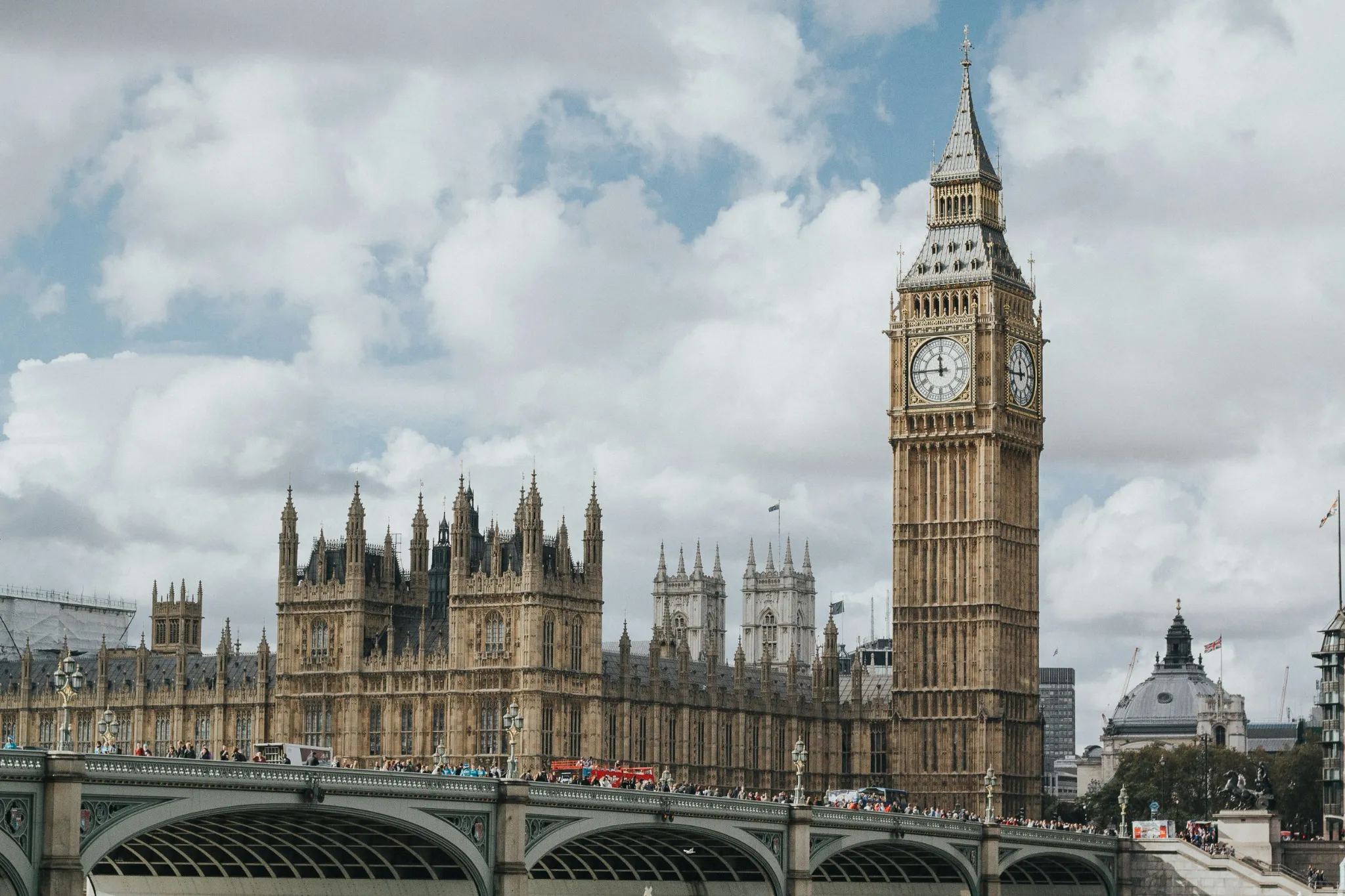 Big Ben e Palazzo di Westminster a Londra con il ponte di Westminster in primo piano sotto un cielo parzialmente nuvoloso